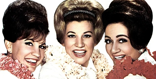 Photo of the Andrews Sisters wearing Hawaiian leis and smiling broadly.