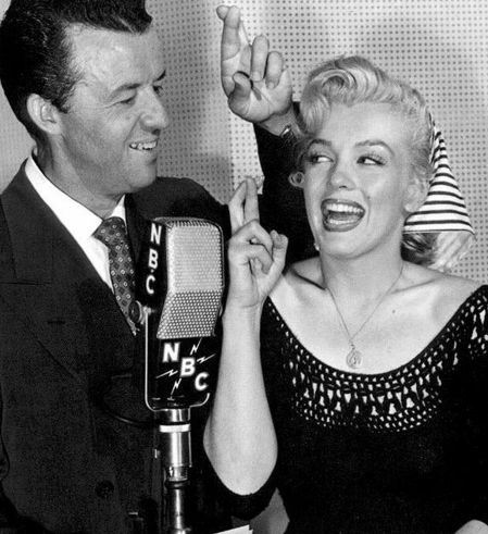 Wendell Niles and Marilyn Monroe with fingers crossed at an NBC Radio microphone in 1952