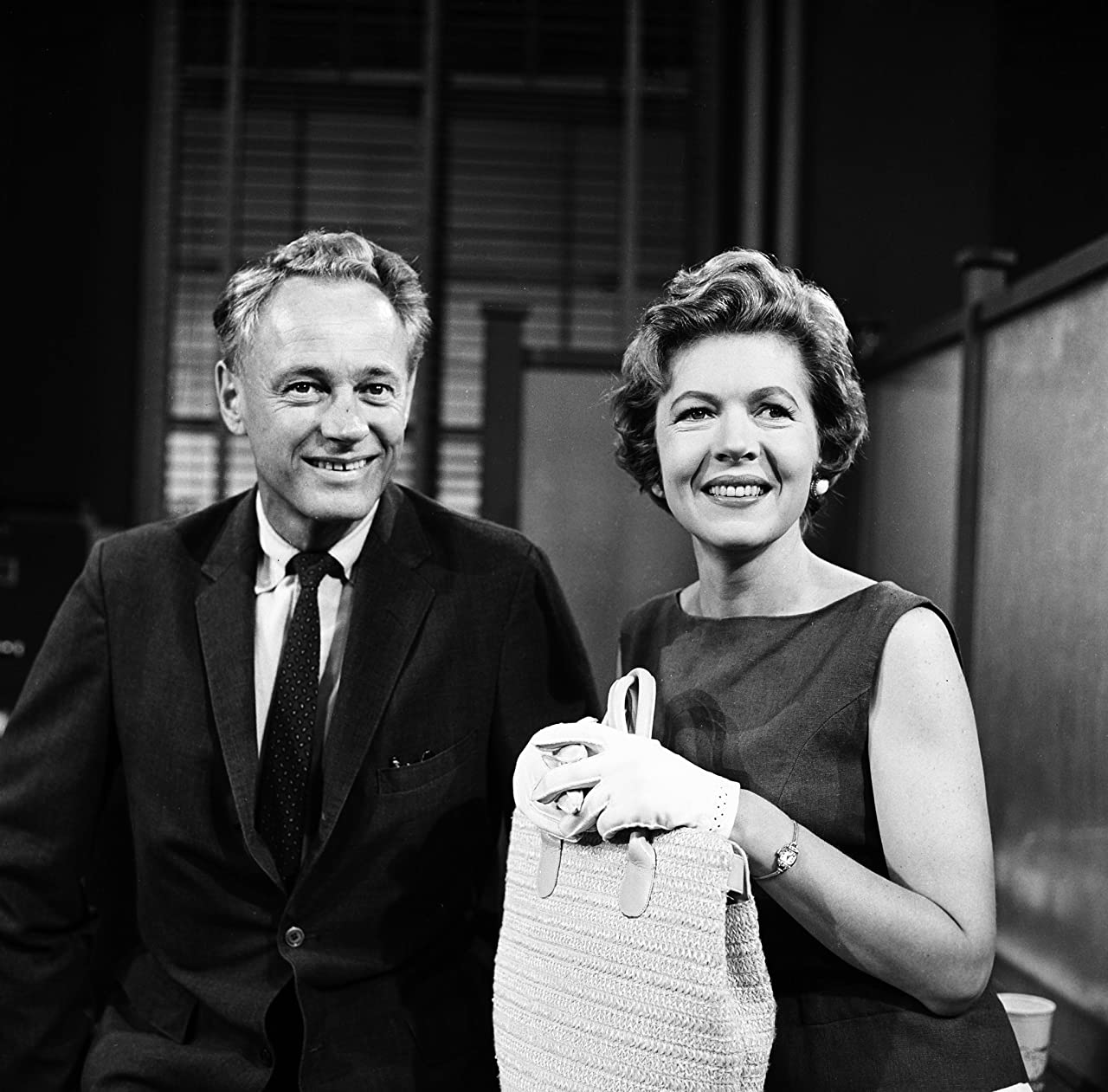 Photo of Augusta Dabney and William Prince appearing as Tracey and Jerry Malone in the Young Dr. Malone TV series in 1958. Both are well-dressed and she's wearing evening gloves and holding a purse.